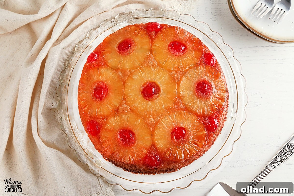 Feast-Worthy Gluten-Free Thanksgiving Desserts 7 gluten-free pineapple upside down cake on a glass cake plate with a cake cutter and plates in the background