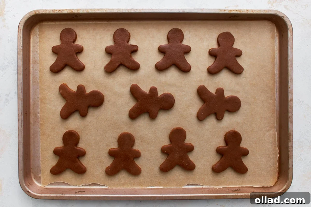 Gluten Free Gingerbread Delights 13 Multiple raw gluten-free gingerbread men cookie dough cutouts arranged on a parchment-lined baking sheet, spaced for even baking.