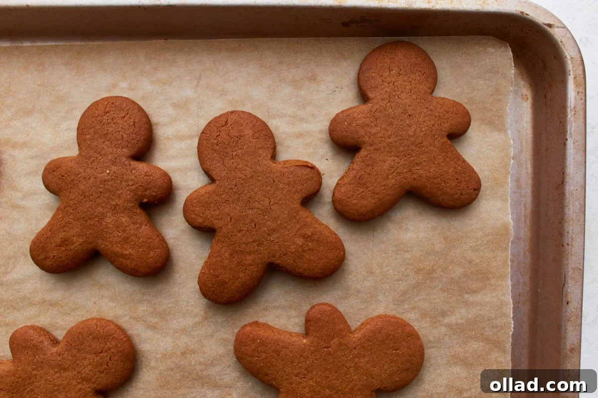Gluten Free Gingerbread Delights 14 A baking sheet filled with freshly baked gluten-free gingerbread men, golden brown and perfectly formed, cooling on parchment paper.