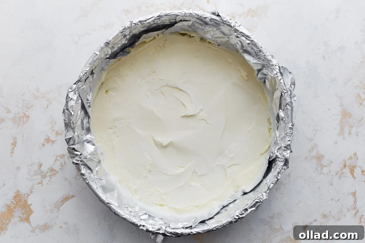 Decadent Gluten-Free Ice Cream Cake 14 A round cake pan lined with foil and filled with smoothed vanilla gluten-free ice cream, ready to be frozen into a solid layer.