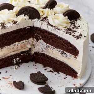 A layered gluten-free chocolate ice cream cake sliced to reveal chocolate cake layers, a vanilla ice cream center with cookie pieces, whipped cream frosting, and decorative chocolate cookies and rosettes on top.