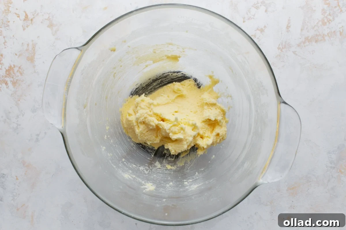 Chewy Gluten-Free Snickerdoodle Delights 5 A clear glass mixing bowl holds a light and fluffy mixture of creamed butter and granulated sugar, indicating the successful completion of the first step in preparing the snickerdoodle cookie dough.