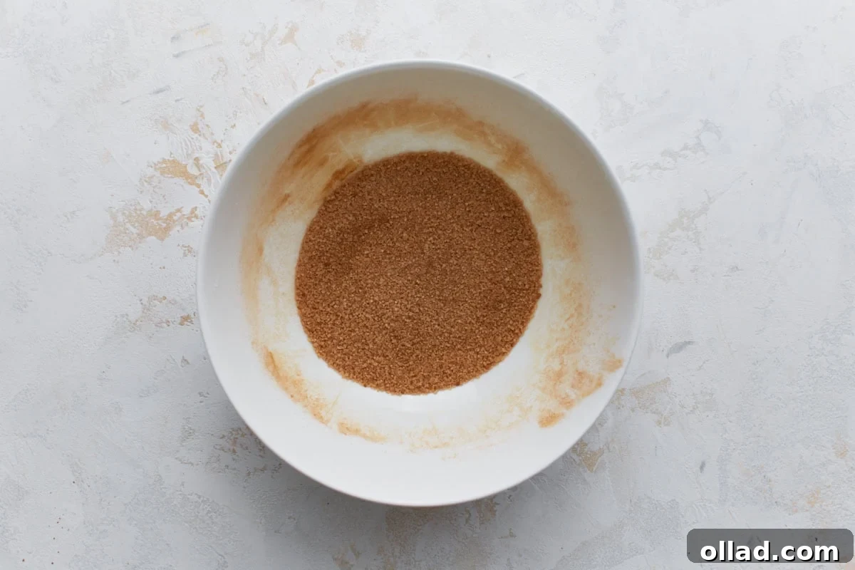 Chewy Gluten-Free Snickerdoodle Delights 9 A crisp white bowl holds a neatly prepared mixture of granulated sugar and fragrant ground cinnamon, perfectly blended and ready for rolling the gluten-free snickerdoodle cookie dough.