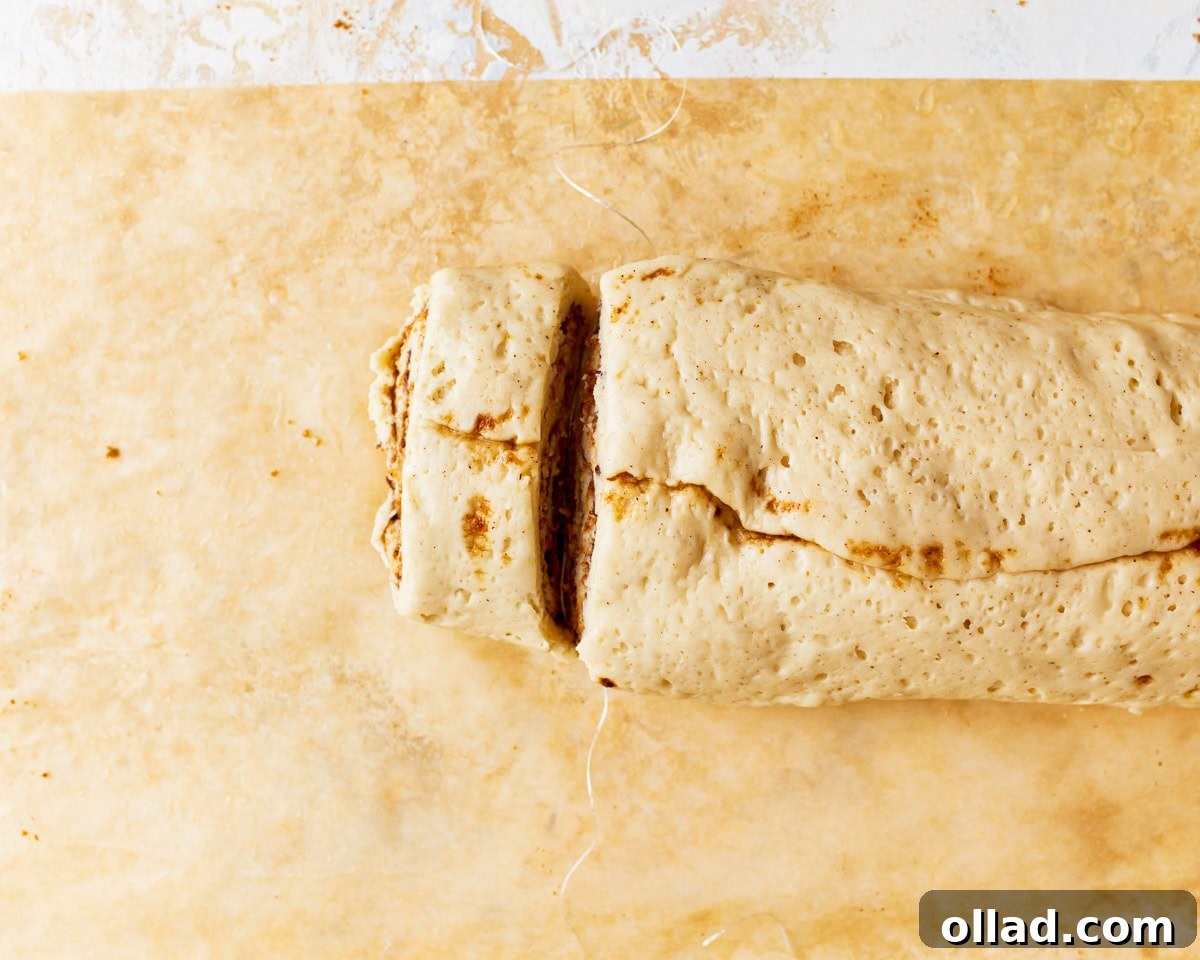 Irresistible Gluten-Free Cinnamon Rolls 17 cutting individual cinnamon rolls from a log of dough.