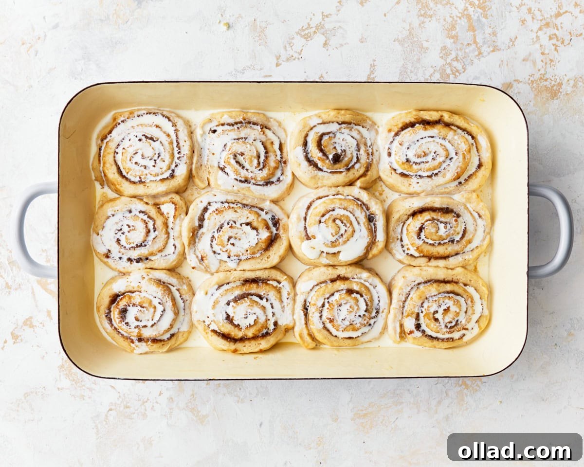 Irresistible Gluten-Free Cinnamon Rolls 19 cream poured over unbaked cinnamon rolls in a tray.