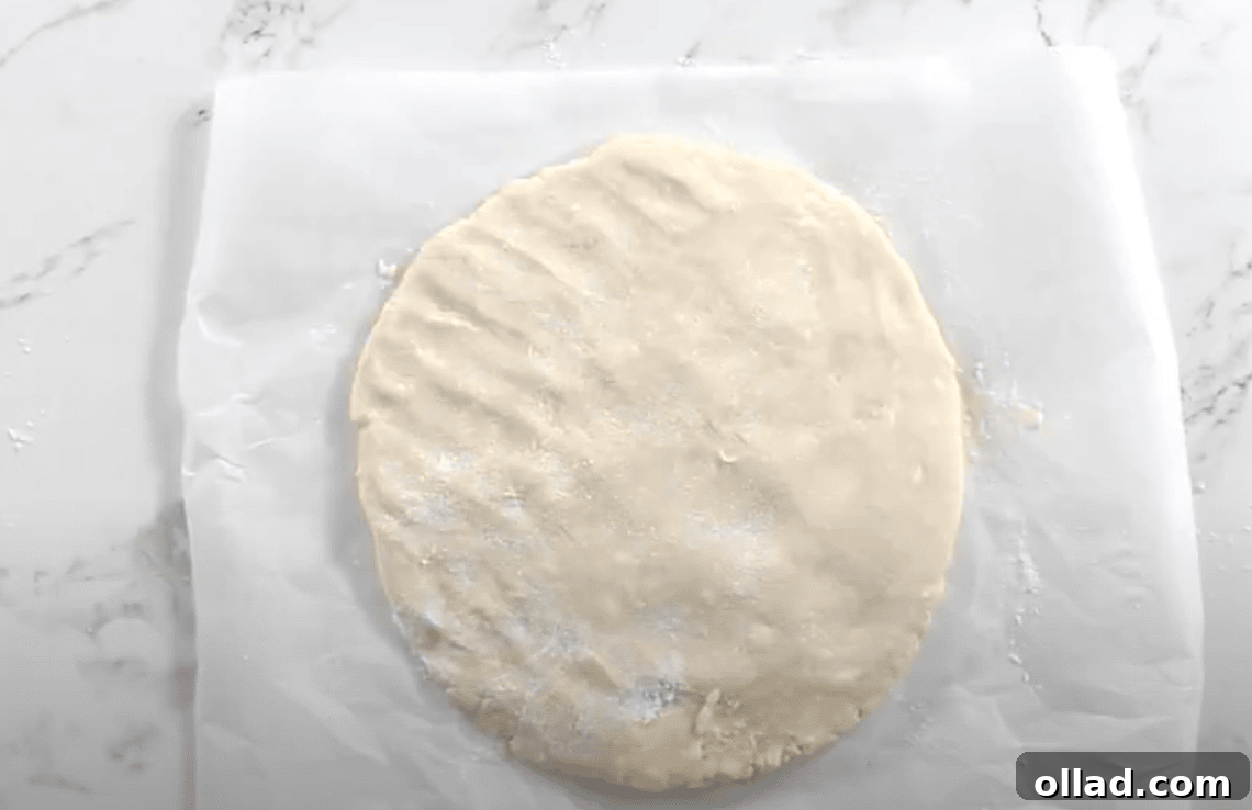 A final round of folded and flattened dough, lightly dusted with flour and ready to cut.