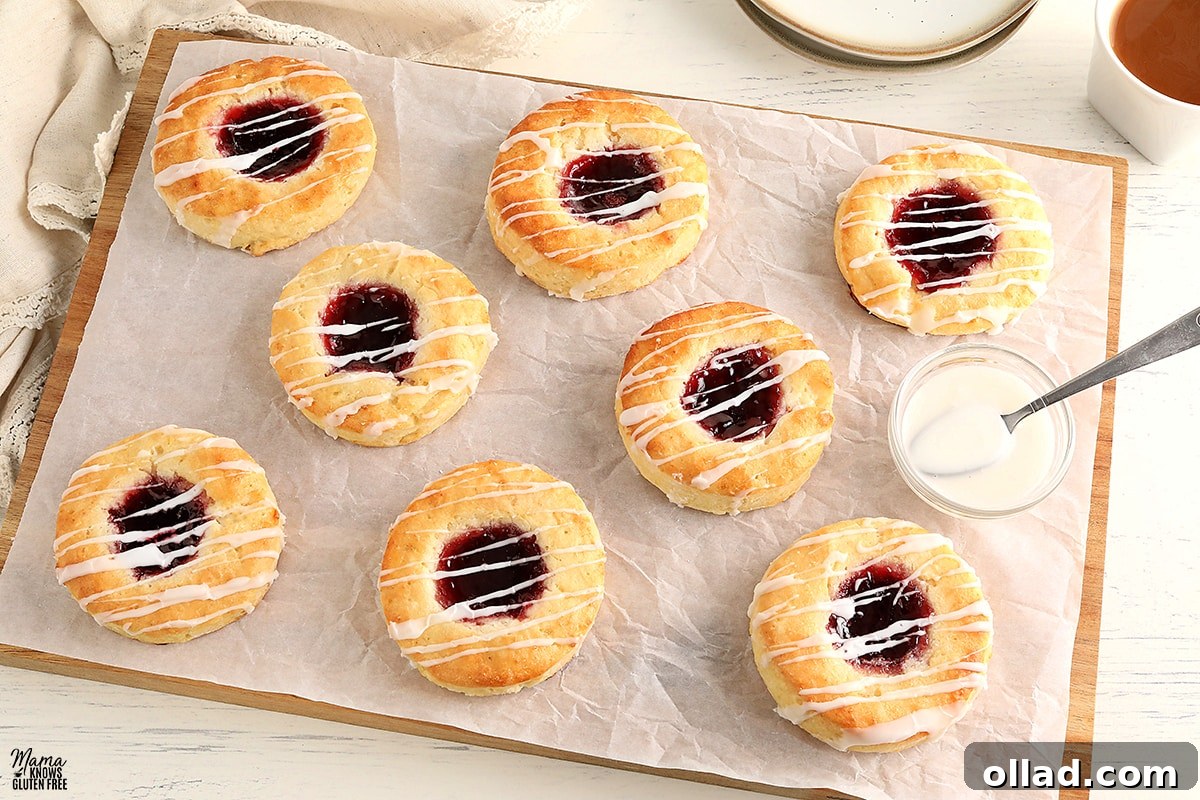 gluten-free Danish on parchment paper with a bowl of glaze and a spoon