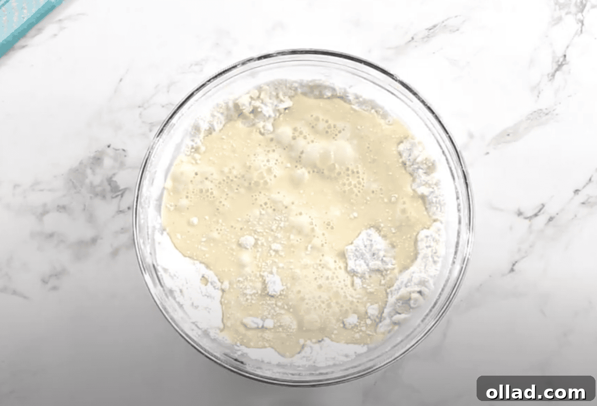 The milk and egg mixture is poured into the flour mixture, starting to form a wet, sticky dough.