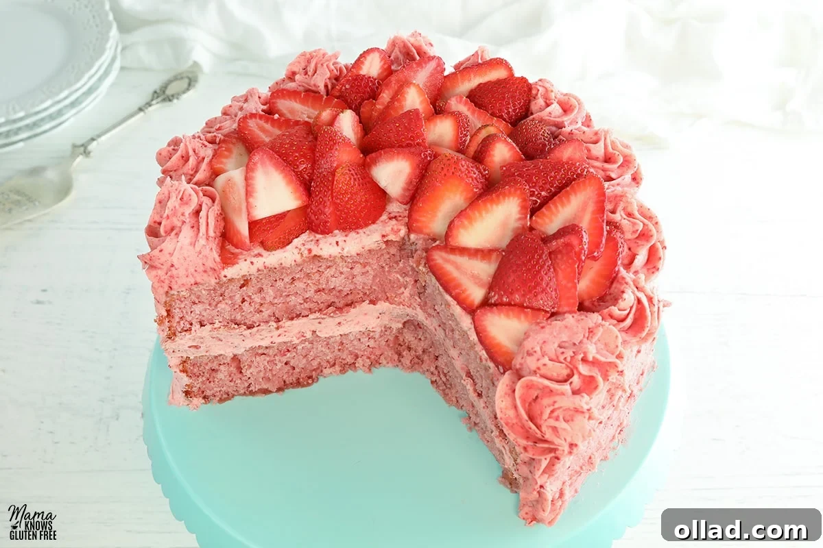 A slice of gluten-free strawberry cake on a blue cake stand, showcasing its moist texture and pink hue.