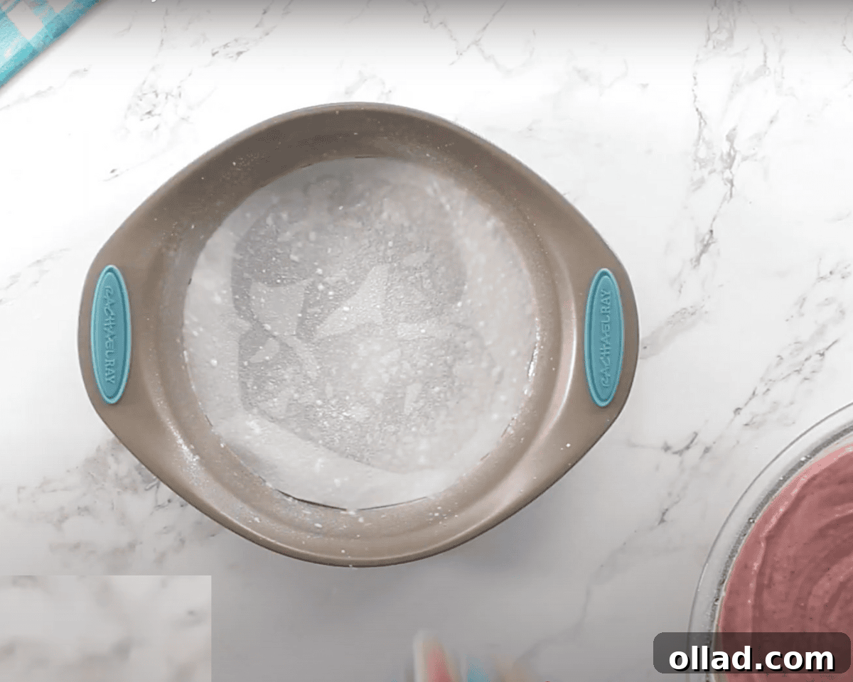 A round cake pan sprayed with gluten-free cooking oil spray sits on a white marble surface, ready for the batter to be poured in.
