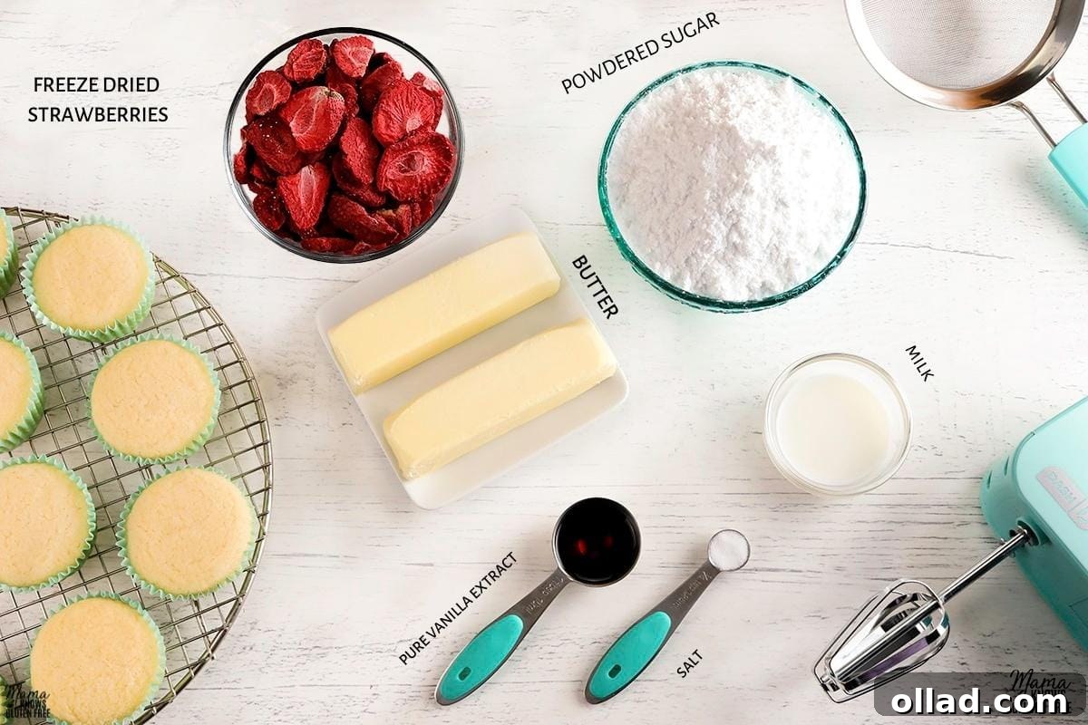 All the essential ingredients for making strawberry frosting laid out, with cupcakes on a cooling rack in the background