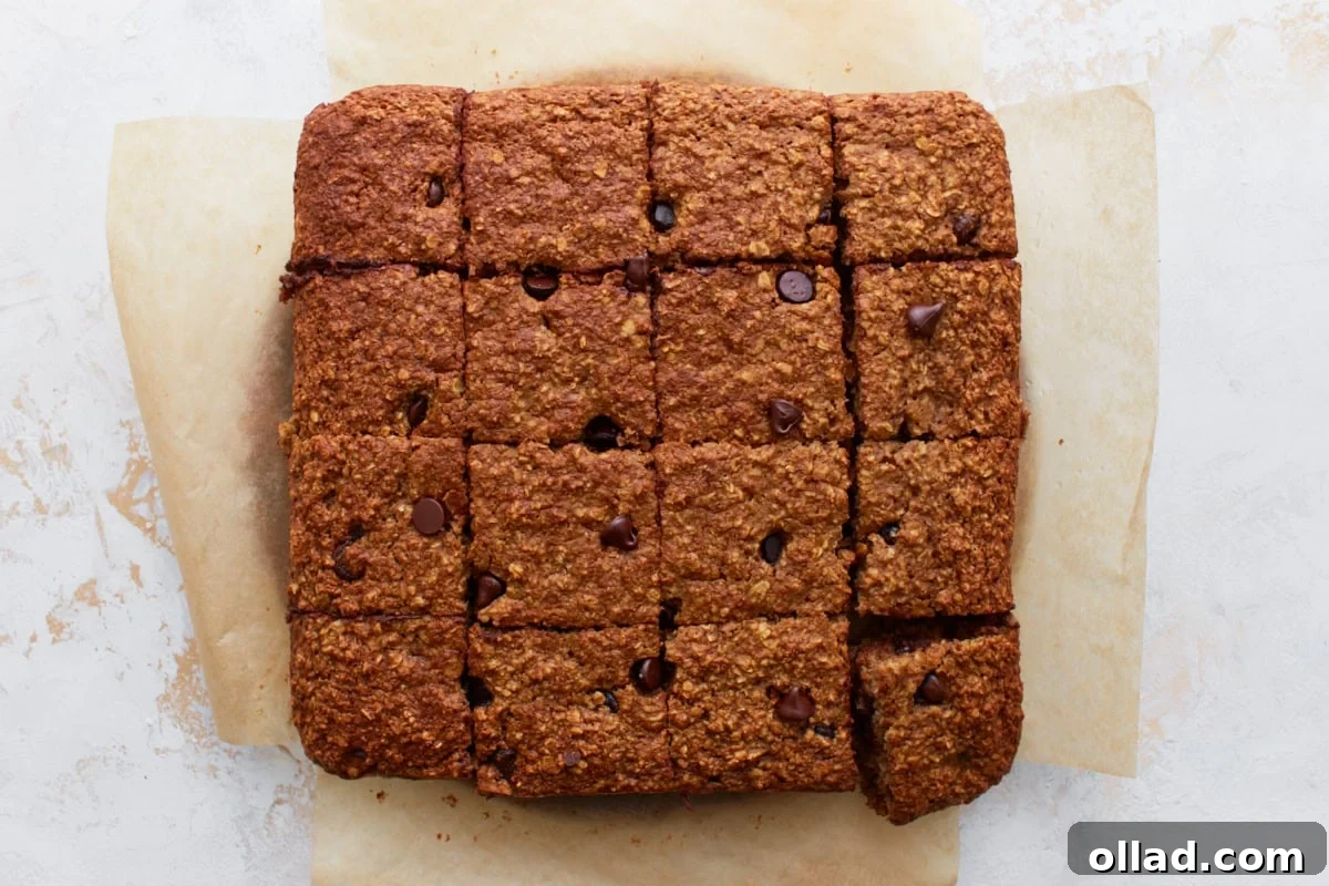 Baked oatmeal bars sliced into 16 even squares on parchment paper, ready to serve.