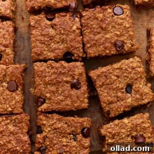 Close-up of sliced baked oatmeal bars with chocolate chips on a wooden surface, showing a golden-brown, chewy texture.