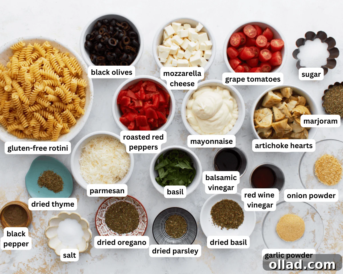 A flat lay photograph displaying all the fresh and pantry ingredients required for making a Creamy Italian Pasta Salad, including gluten-free pasta, various vegetables, and dressing components.