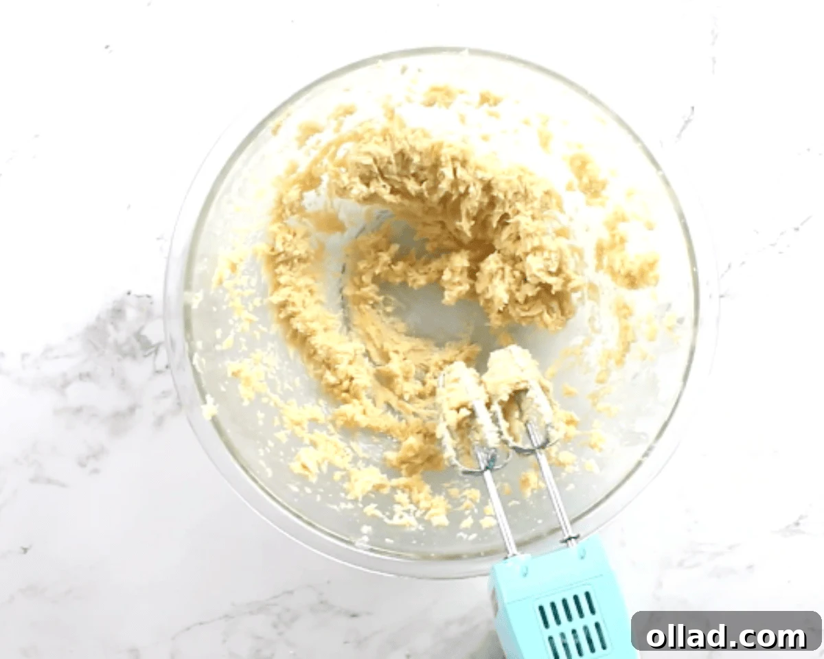 Butter, sugars, egg yolk, and vanilla mixed together into a smooth cookie dough base in a glass bowl.