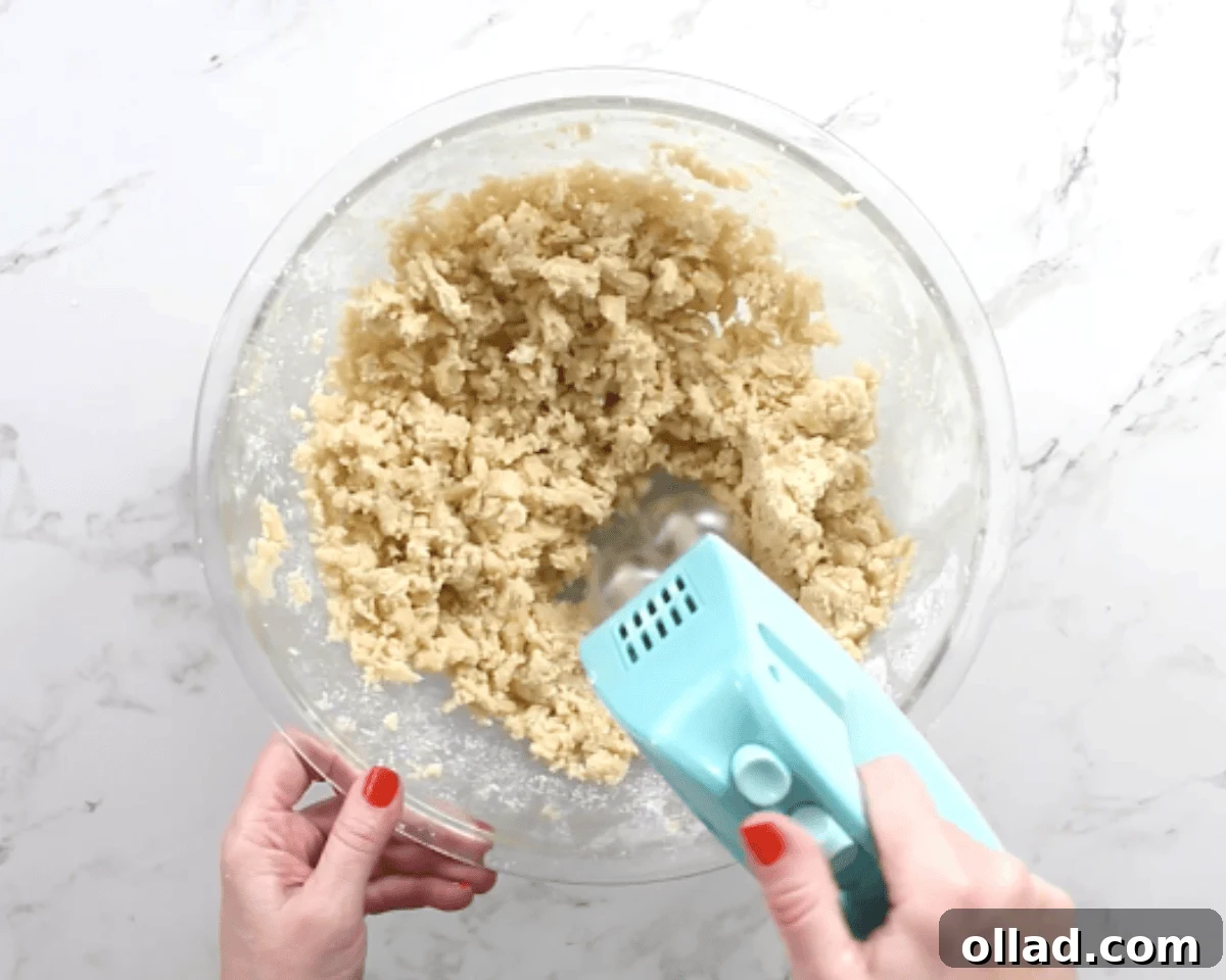 Mixing the batter for gluten-free thumbprint cookies in a glass bowl.