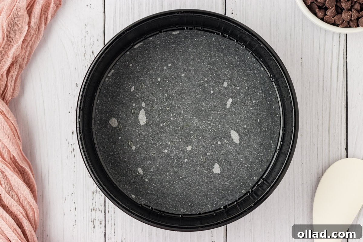 An 8-inch round cake pan meticulously lined with a circular piece of parchment paper and generously greased with cooking spray, ready for the batter.