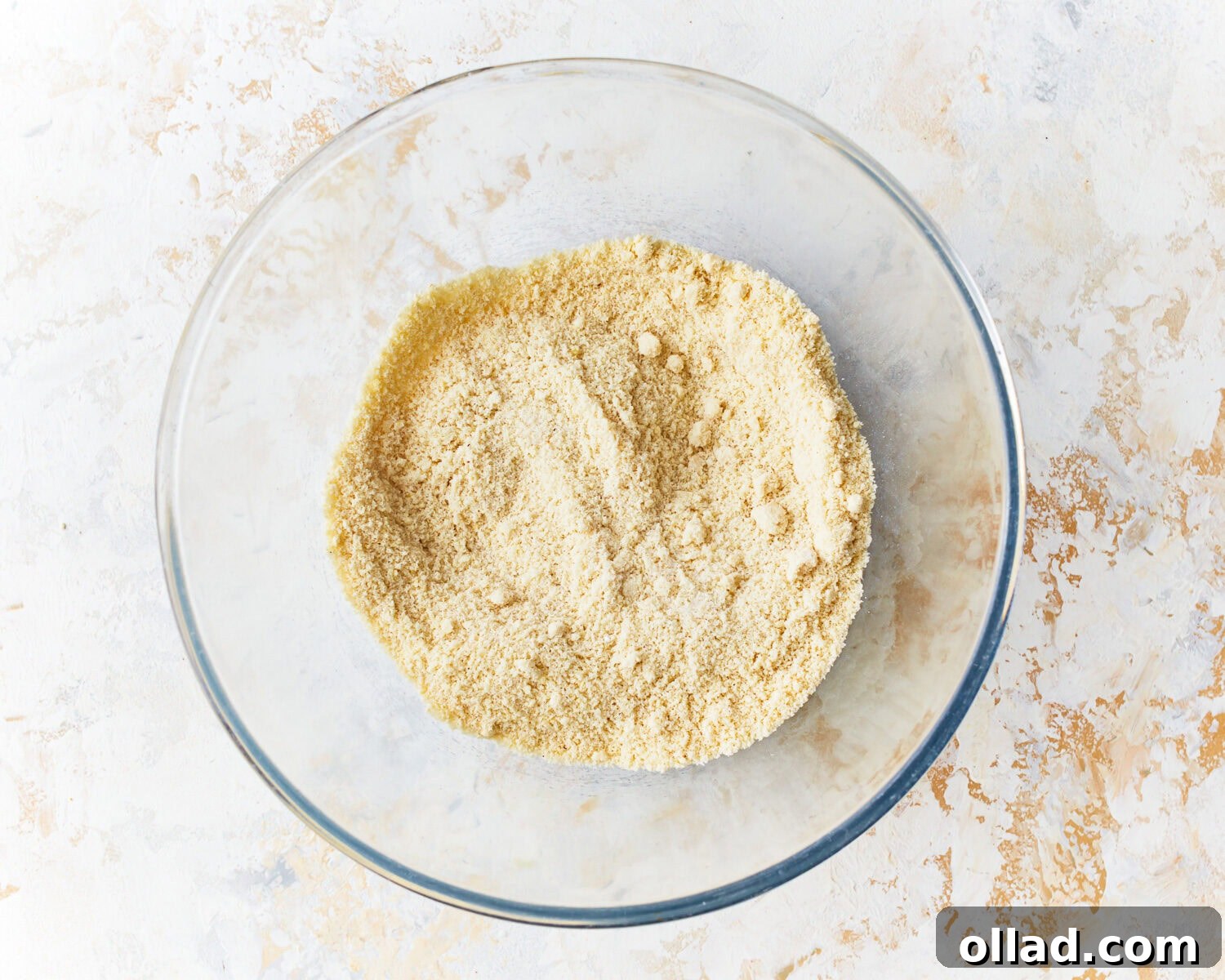 Dry ingredients for almond flour pancakes, including superfine blanched almond flour, baking powder, baking soda, salt, and granulated sugar, mixed in a clear glass bowl.