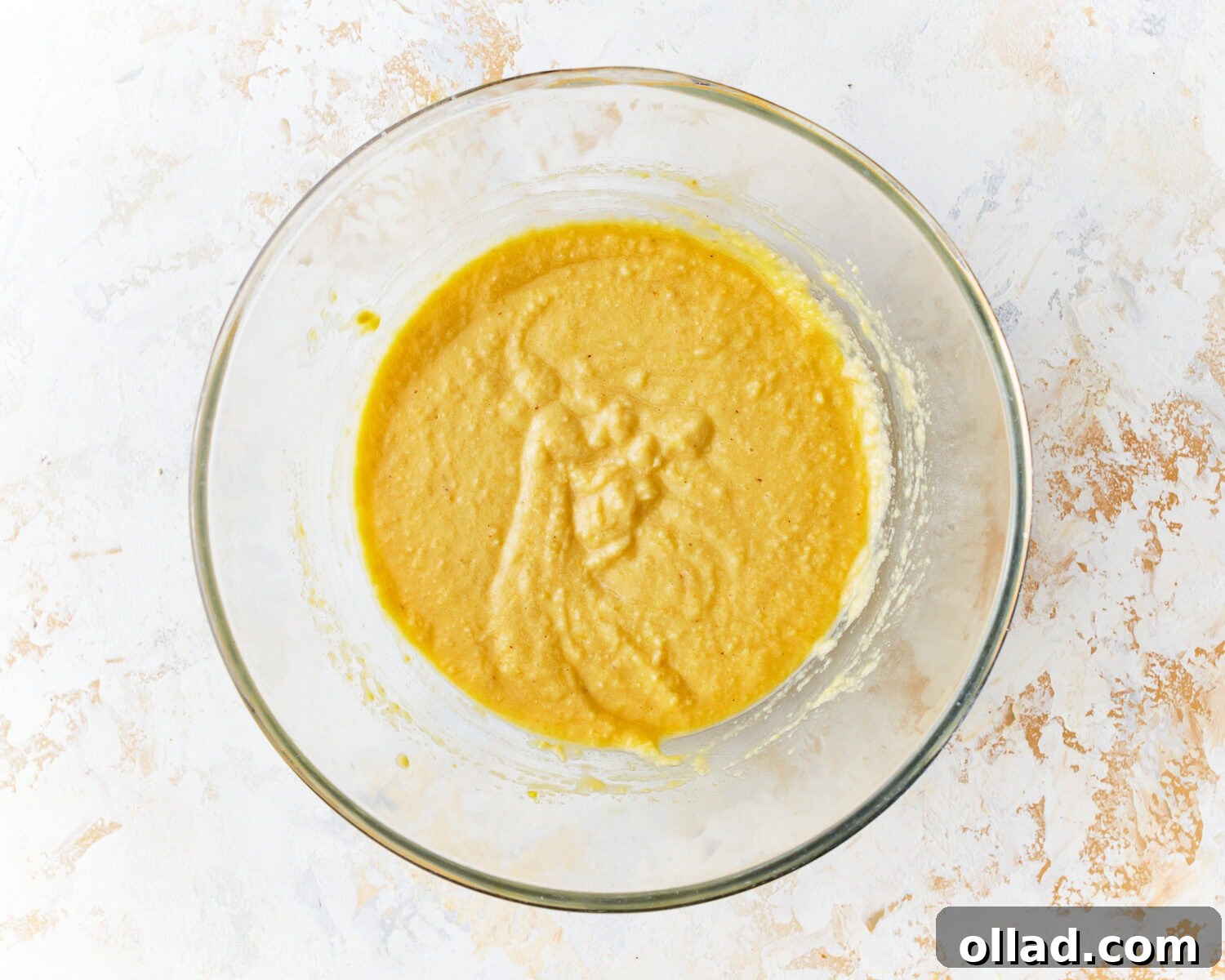 A smooth and thick almond flour pancake batter resting in a clear glass mixing bowl, ready for cooking.