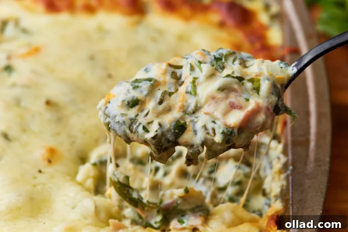 Spoon scooping out hot spinach dip from a baking dish