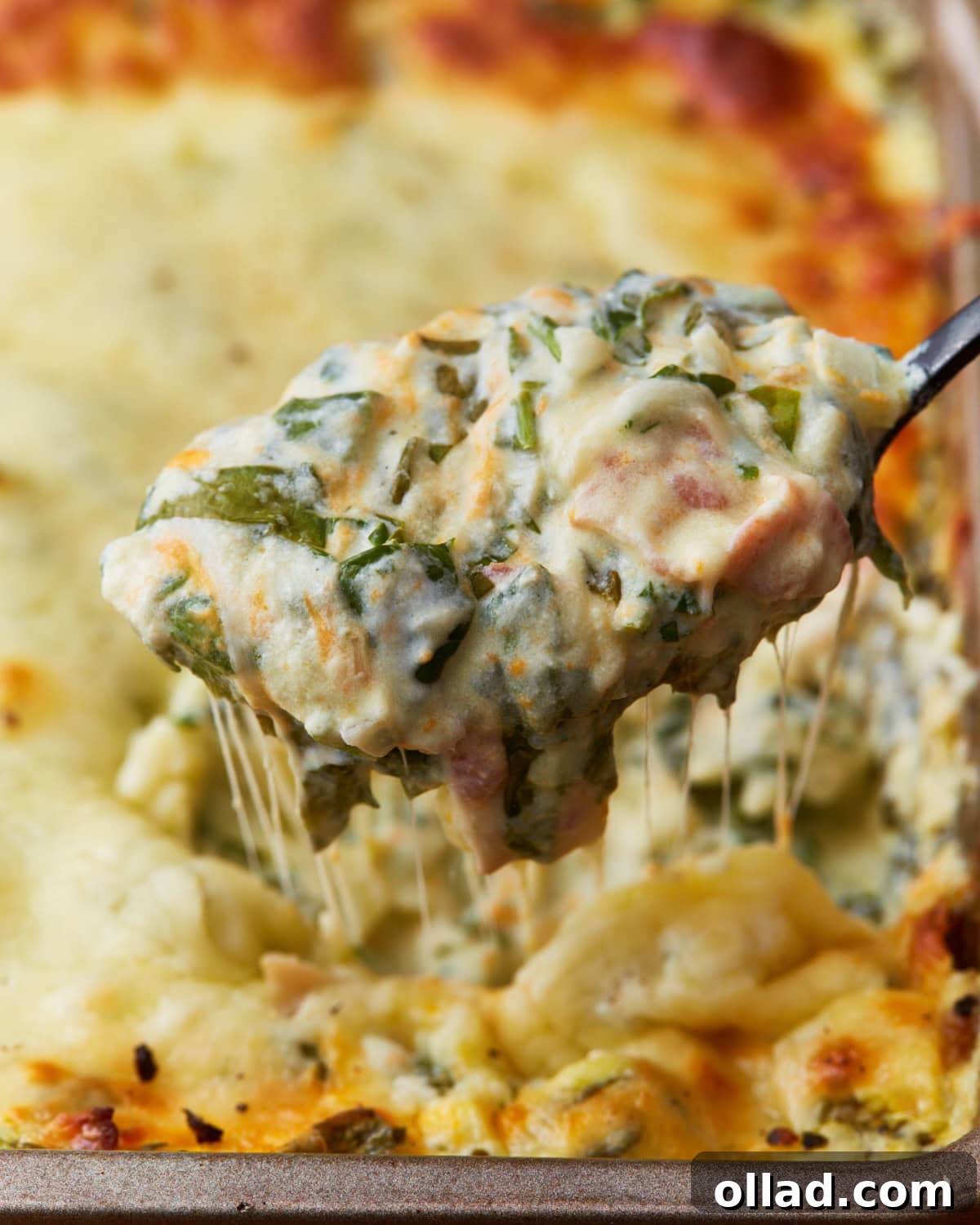 Spoon scooping out some hot spinach dip out of a baking tin