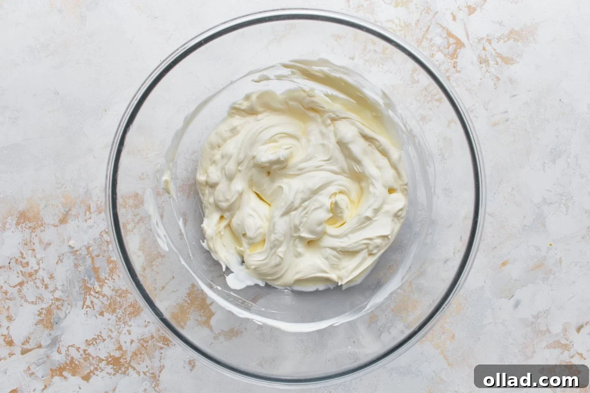 Cream cheese and sour cream mixture in glass bowl on light surface
