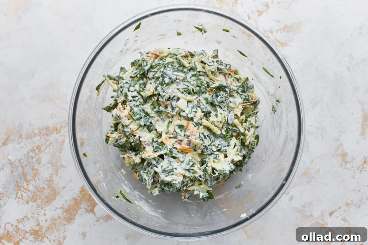 Hot spinach dip filling mixed in glass bowl resting on light surface