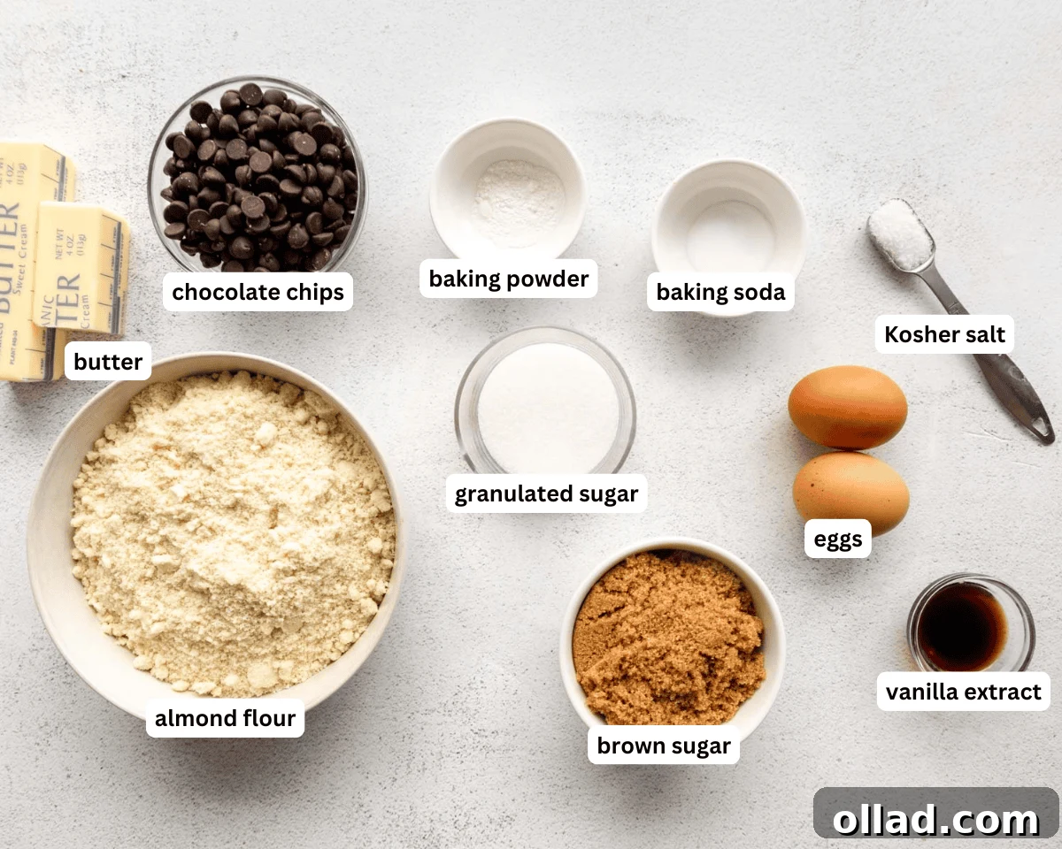 All ingredients for almond flour chocolate chip cookies laid out on a table: almond flour, butter, sugars, eggs, vanilla, chocolate chips, baking powder, baking soda, salt.