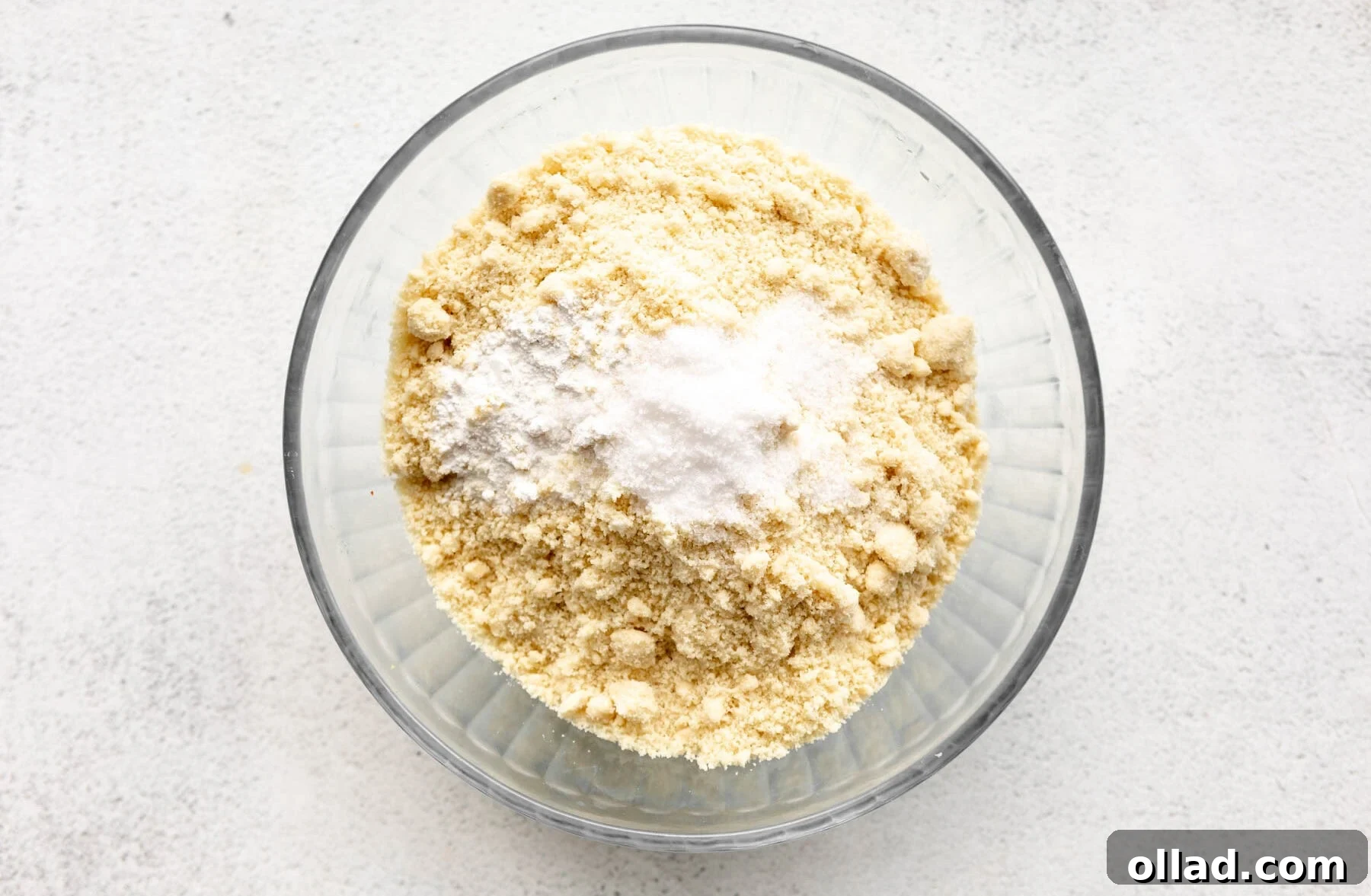 Almond flour, baking soda, baking powder, and salt measured in a glass bowl, ready to be mixed.