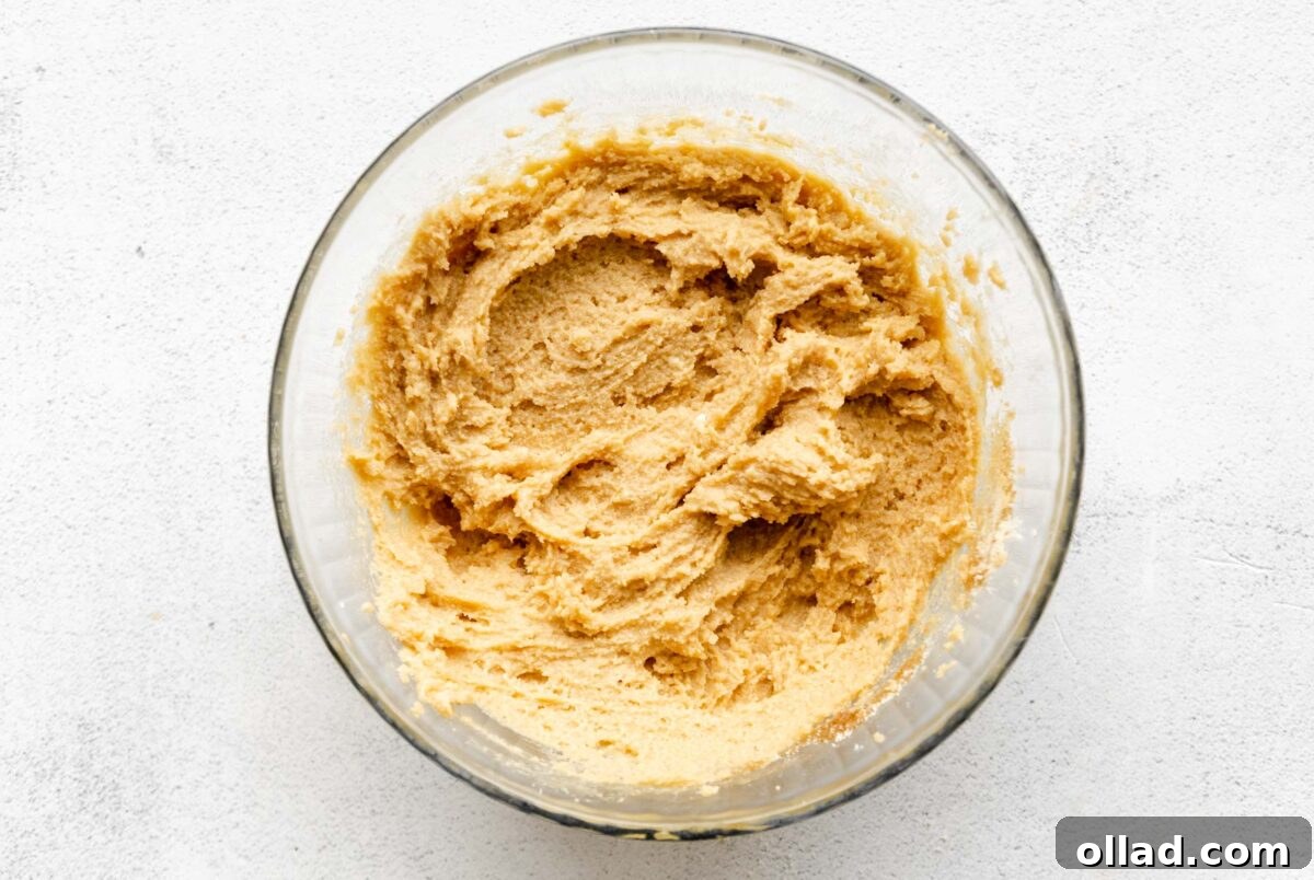 Thick and sticky almond flour cookie dough forming after dry ingredients are added to the wet mixture.