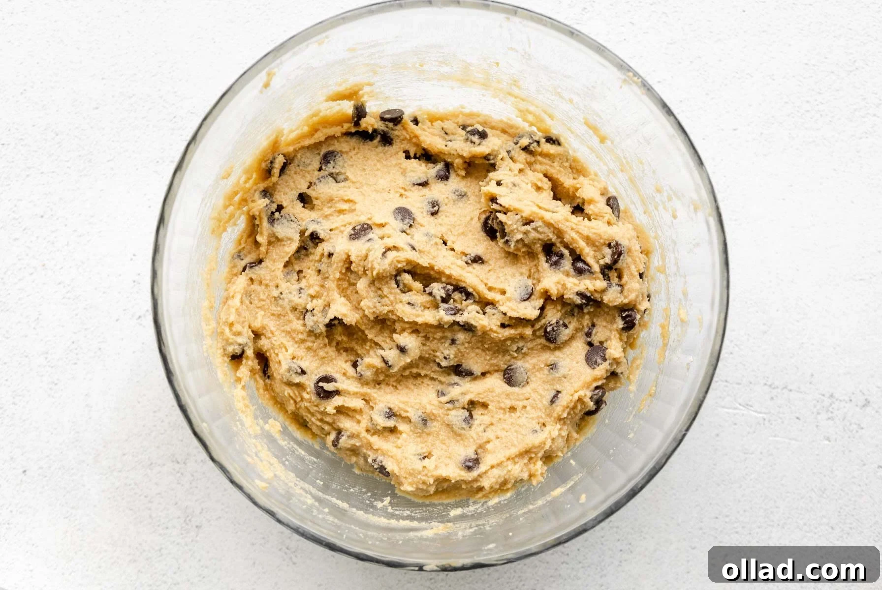 Almond flour chocolate chip cookie dough with evenly distributed chocolate chips in a glass bowl.