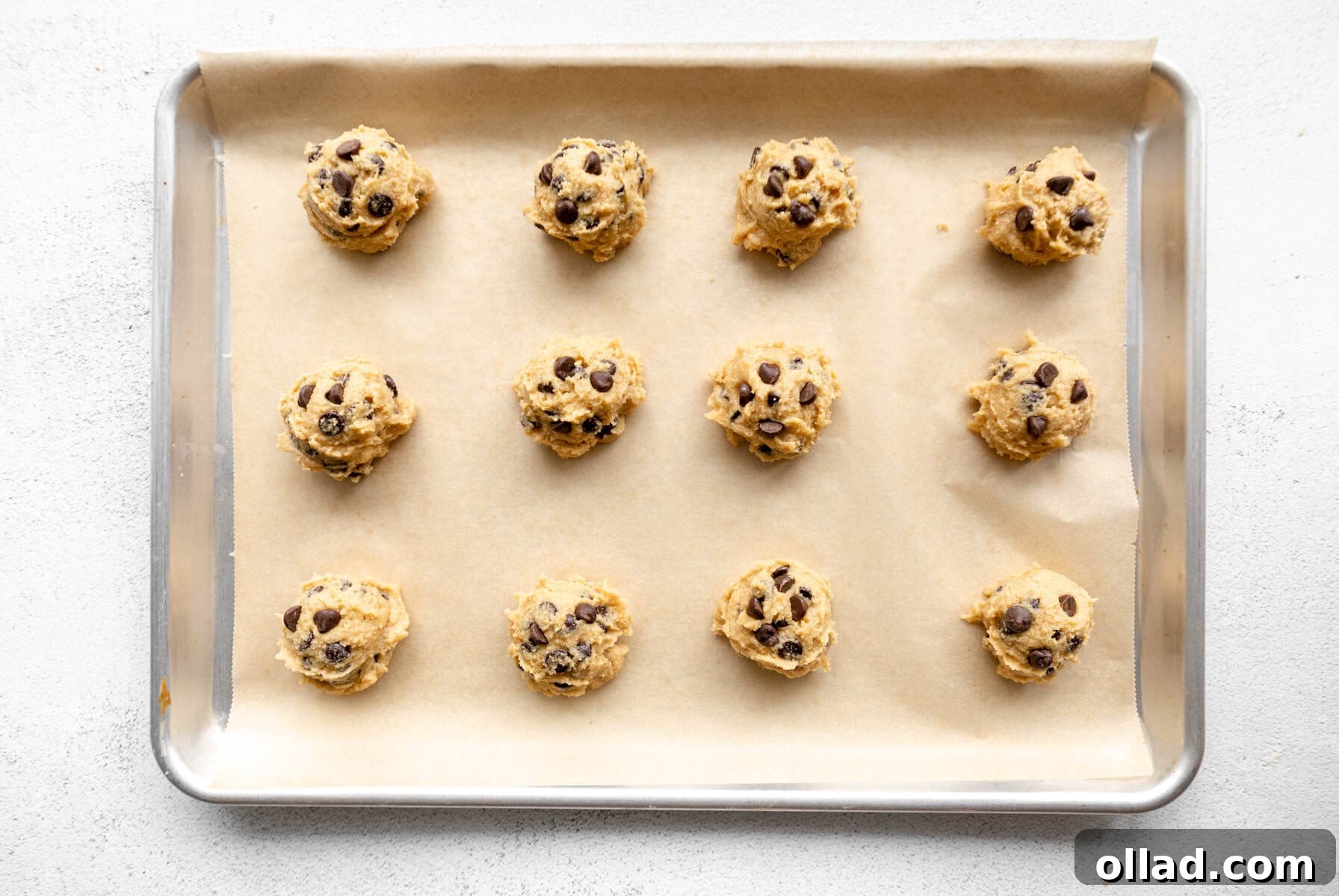 Portioned almond flour cookie dough balls placed on a parchment paper-lined baking sheet, ready for the oven.
