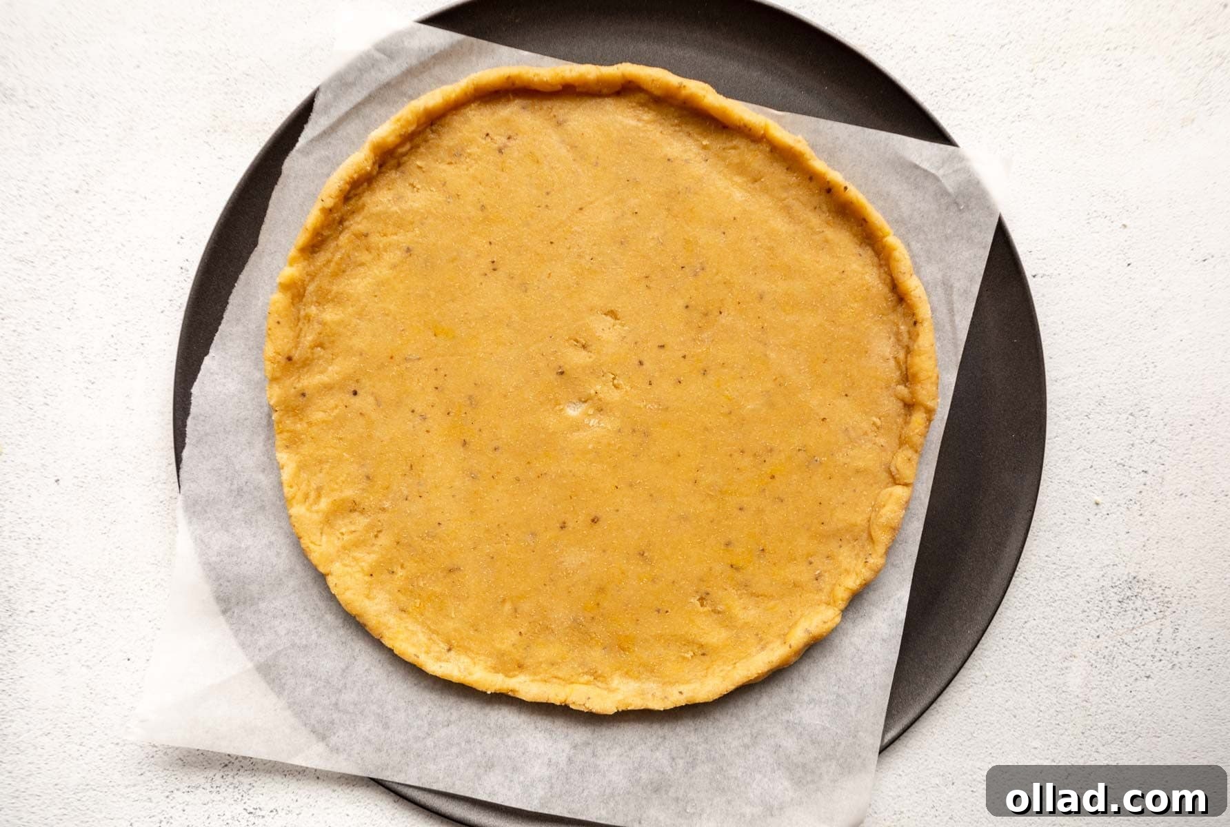 Almond flour pizza dough rolled into a perfect circle on a parchment-lined pizza pan.