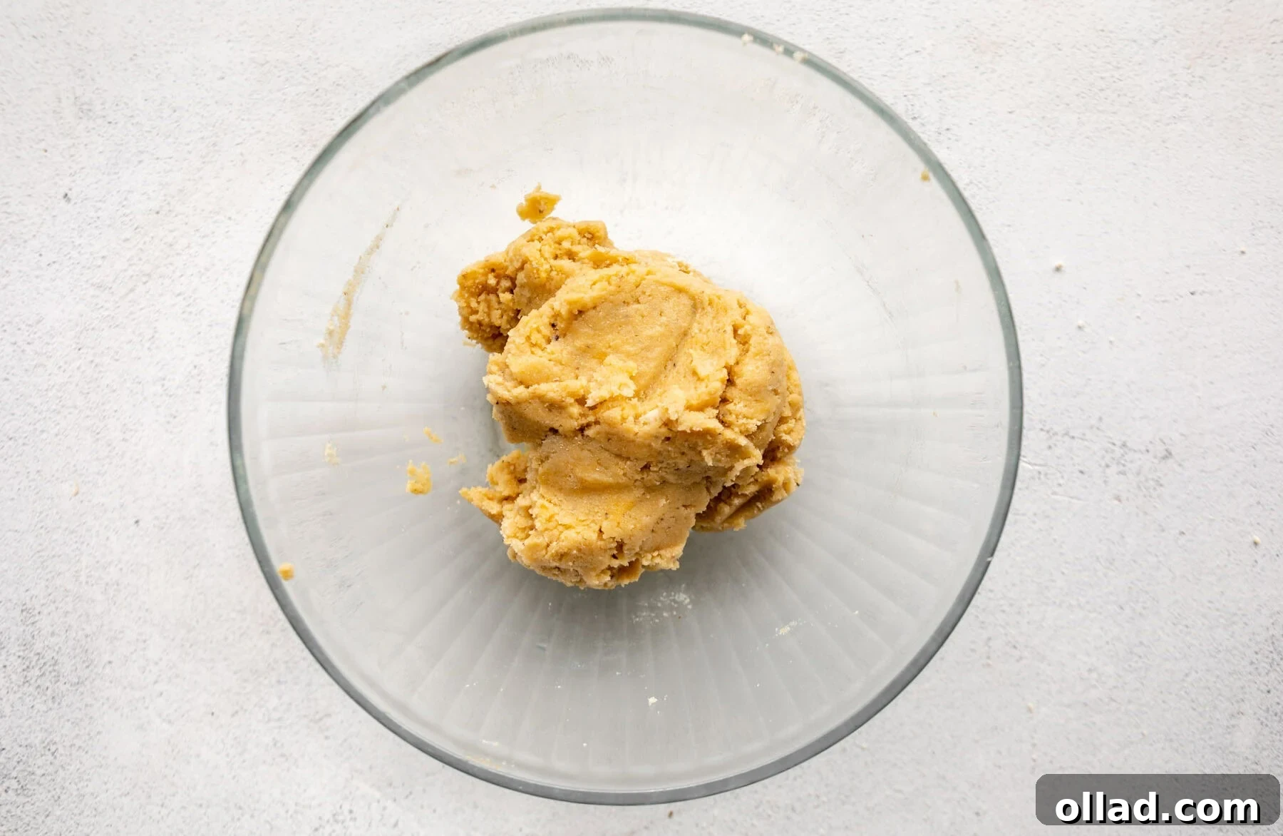 A ball of mixed almond flour pizza dough resting in a glass bowl.