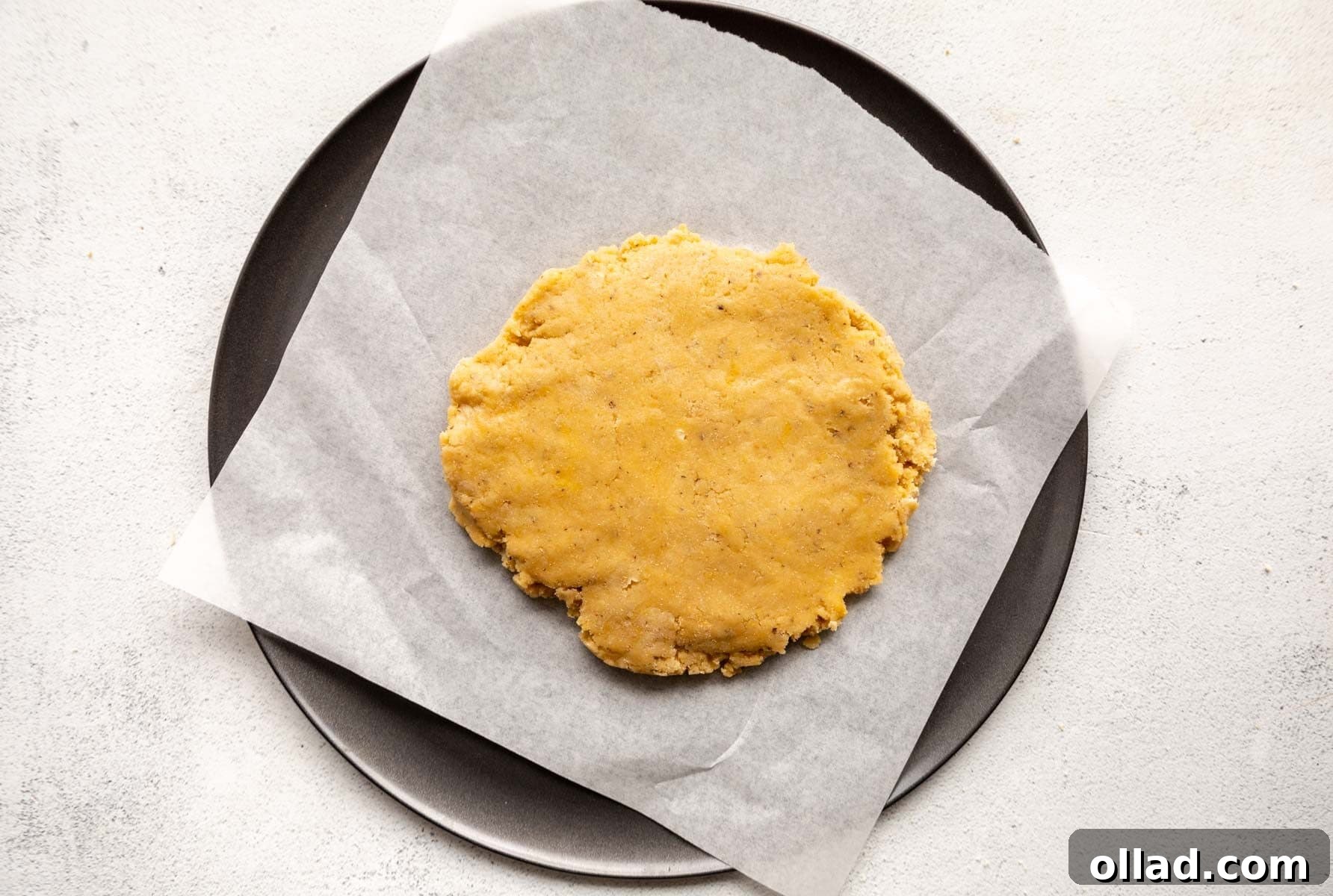 Almond flour pizza dough placed on a parchment-lined pizza pan, ready for rolling.