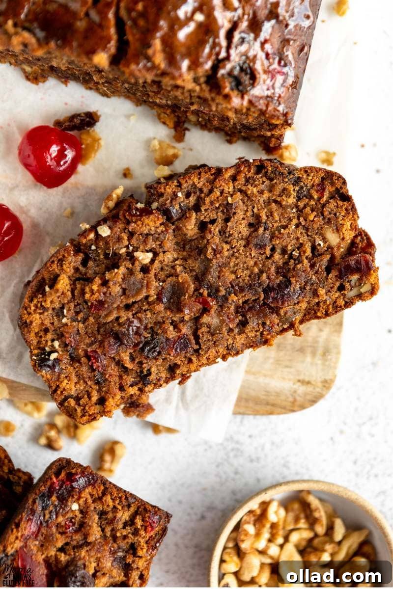 Deliciously Flourless Fruitcake 4 Overhead shot of a slice of Gluten-Free Fruit Cake on parchment paper and wooden board.