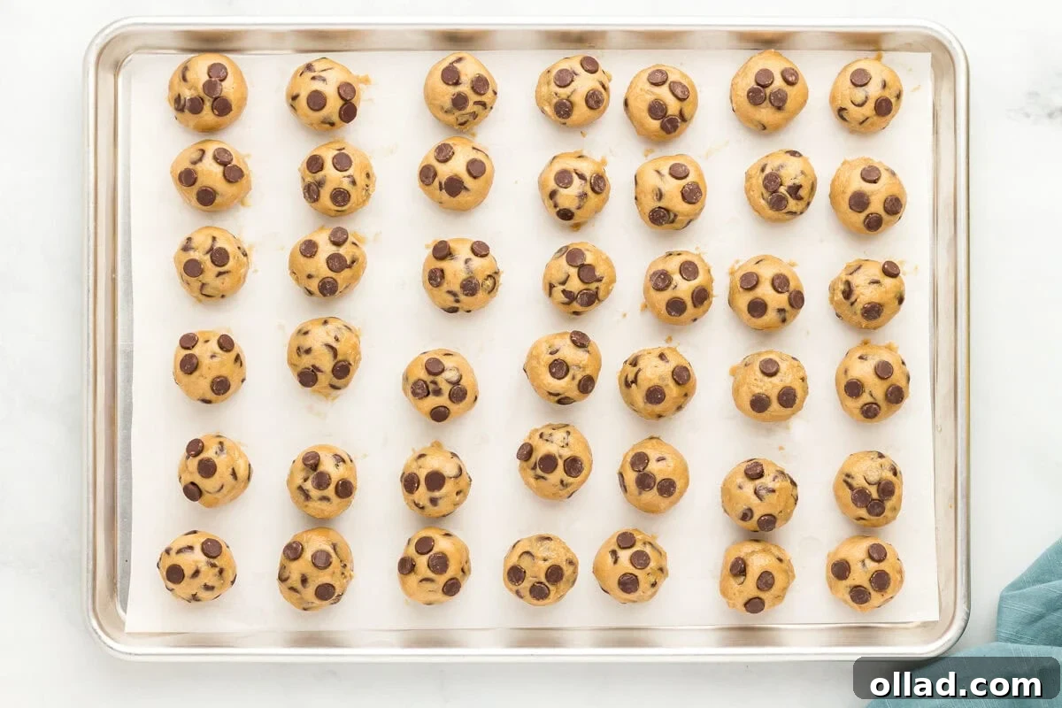 A perfectly rolled ball of oat flour chocolate chip cookie dough with extra chocolate chips pressed into the top.