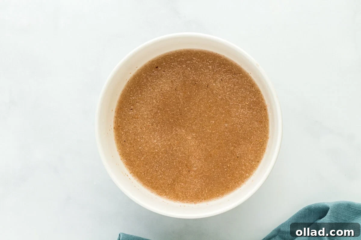 The wet ingredients for gluten-free sourdough bread, including psyllium husk, honey, and water, stirred into a thick gel in a white bowl.