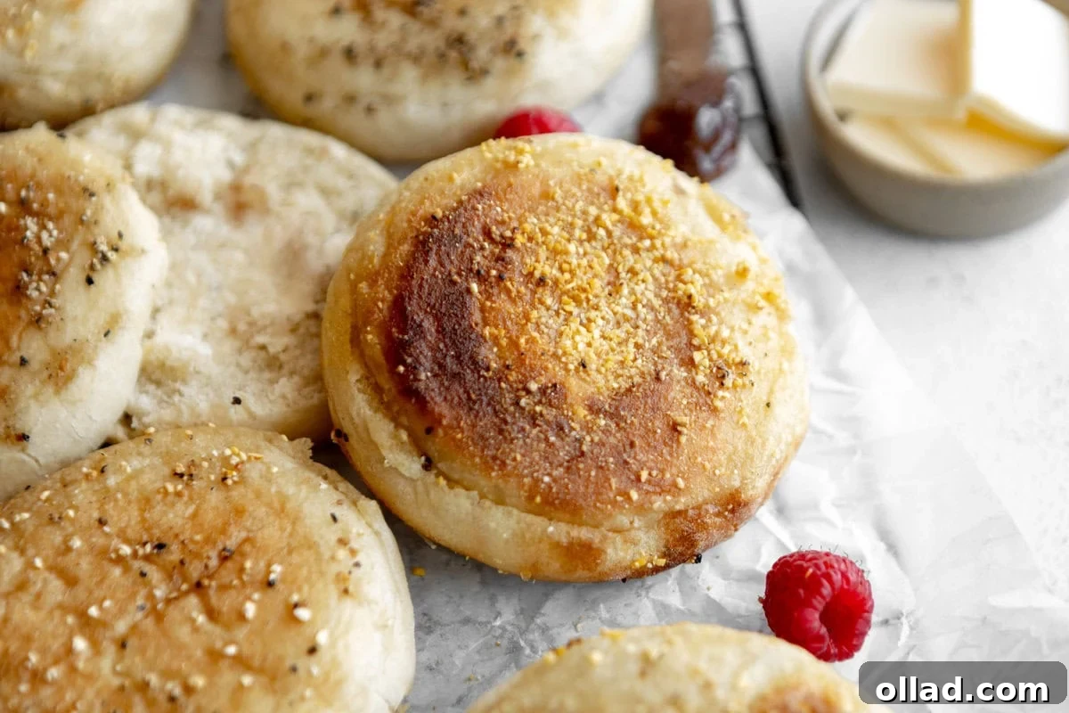 Gluten-free English muffins on parchment paper with fresh raspberries, ready to be enjoyed.