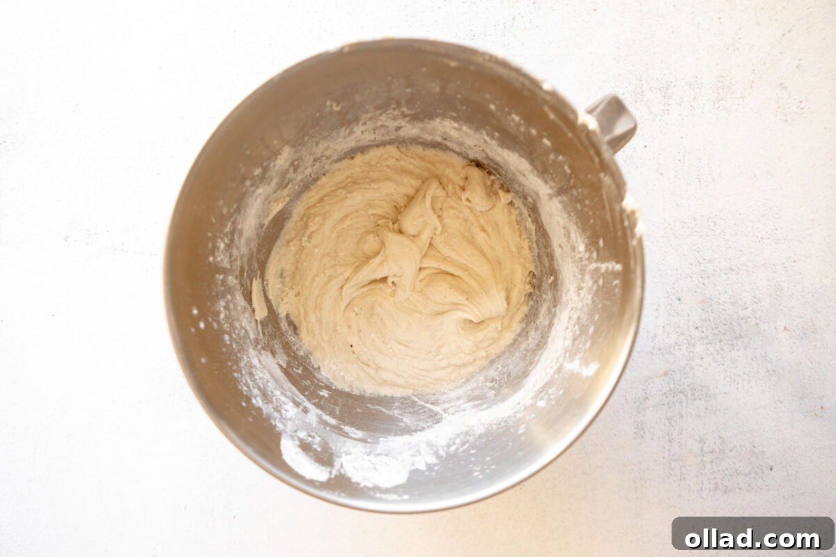 Gluten-free English muffin dough mixing in a stand mixer bowl.