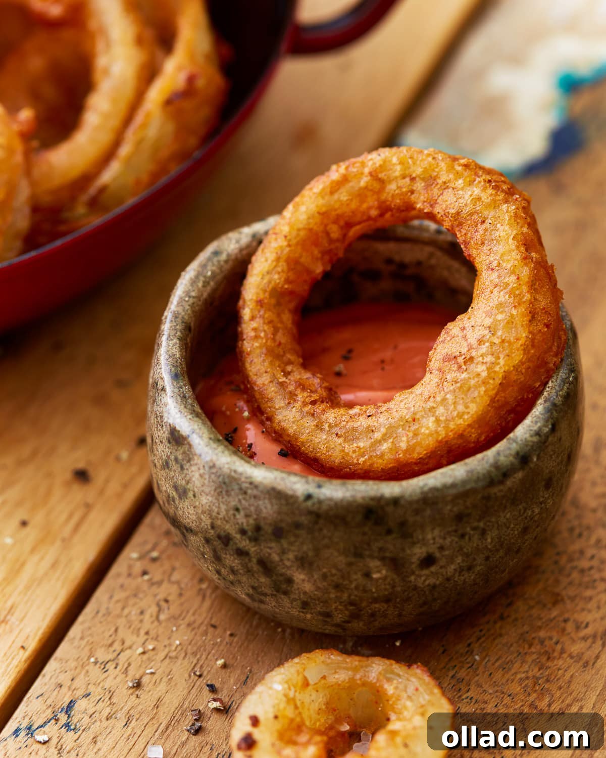 Crispy Gluten-Free Onion Rings 5 A single, perfectly fried gluten-free onion ring dipped into a generous dollop of bright red ketchup, highlighting its golden, crunchy texture.