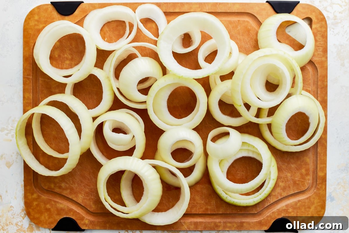 Crispy Gluten-Free Onion Rings 6 Raw onion sliced into uniform ½-inch thick rings, neatly arranged on a cutting board, ready for the next step.