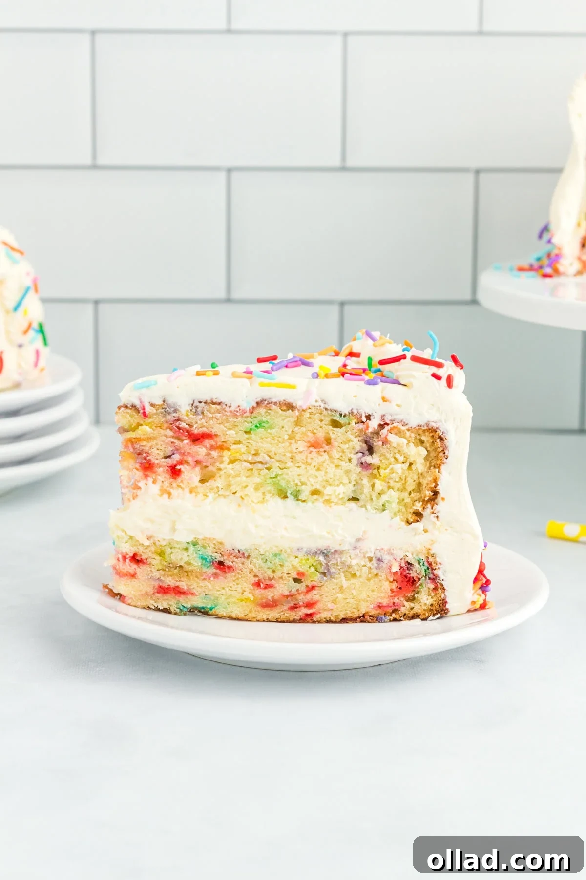 Irresistible Gluten-Free Cake Secrets 6 A close-up of a slice of gluten-free funfetti cake with white buttercream frosting and rainbow sprinkles, showing the colorful sprinkle-filled layers inside.