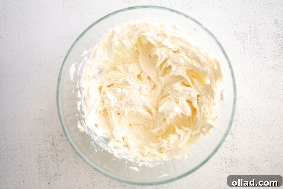 Whipped cream cheese mixture in a clear glass bowl, showing a fluffy, thick texture.