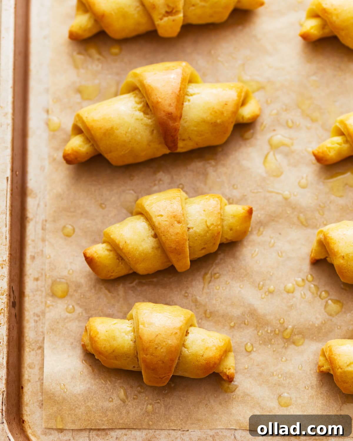 Golden-brown gluten-free crescent rolls cooling on a baking sheet, showcasing their fluffy texture.