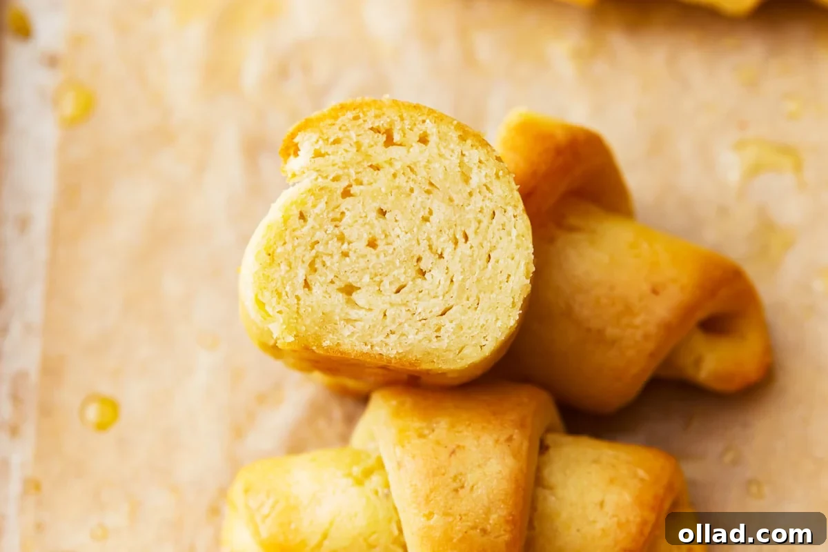 A gluten-free crescent roll halved, revealing its airy and tender interior crumb.
