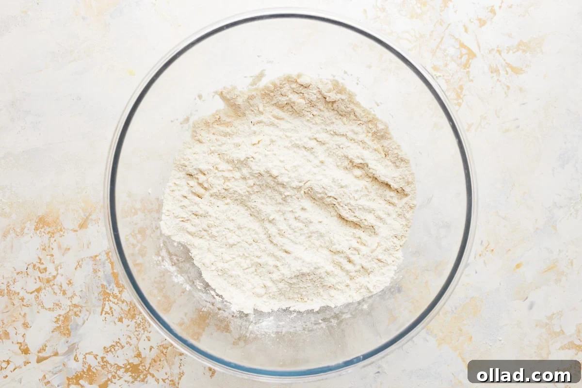 Gluten-free flour and other dry ingredients being whisked in a glass bowl.