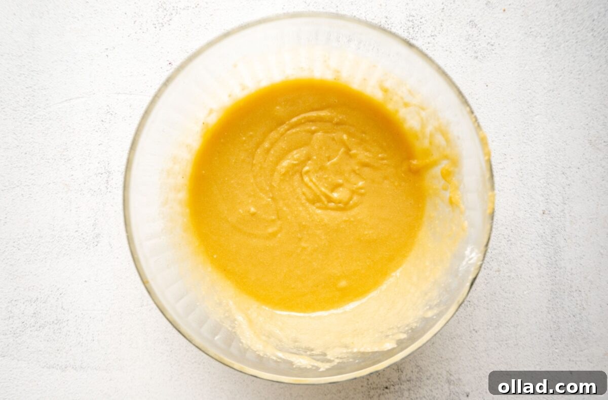 A clear glass bowl showing the wet ingredients mixed with almond flour, forming a thick, creamy batter, ready for the next step in the muffin-making process.