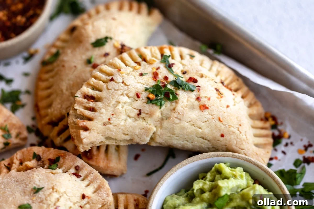 A single gluten-free empanada resting on a baking tray, showcasing its perfectly crimped edge and golden-brown crust.