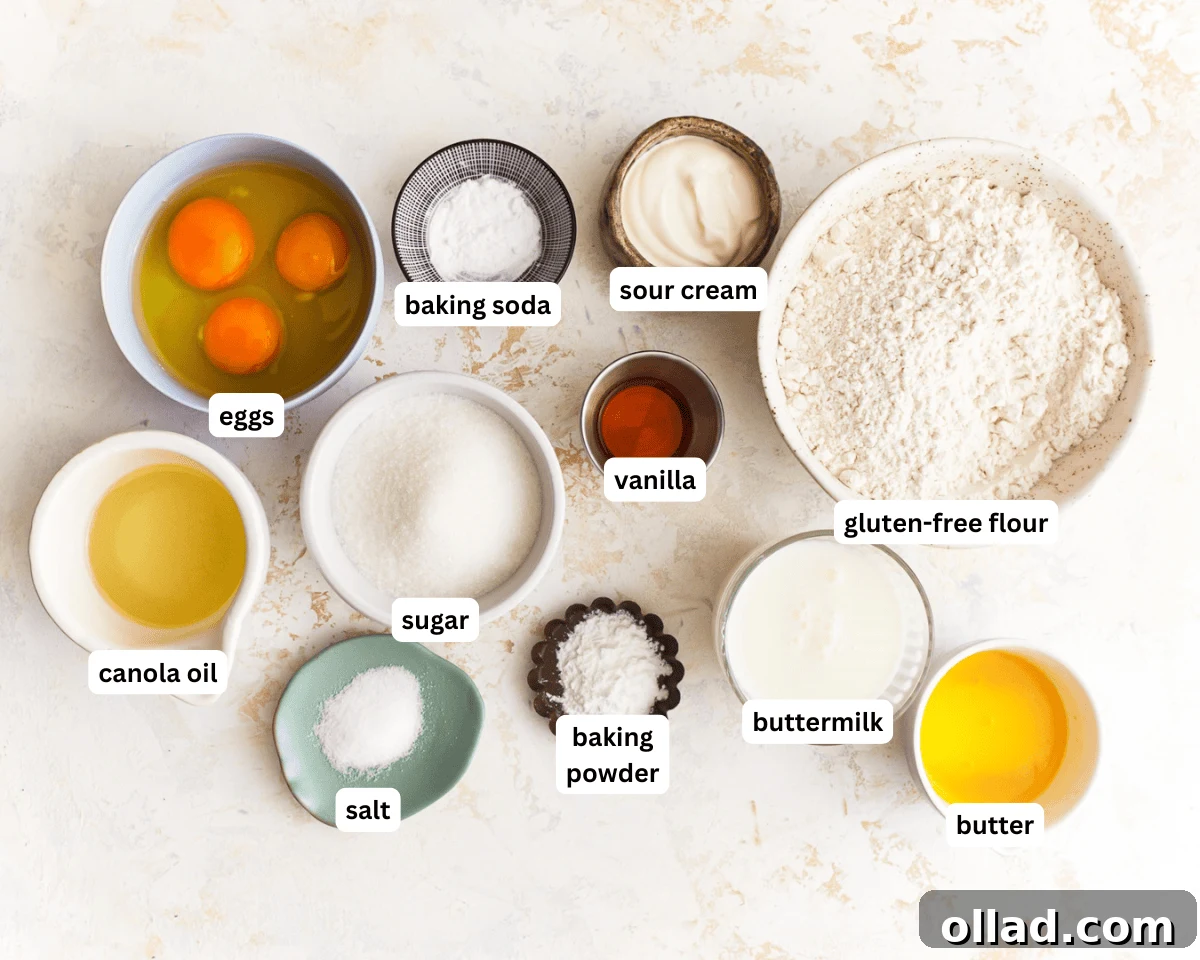 Irresistible Gluten-Free Muffins 3 A colorful array of raw ingredients for baking gluten-free muffins, neatly arranged on a kitchen counter, including eggs, butter, buttermilk, sour cream, gluten-free flour, and vanilla extract.